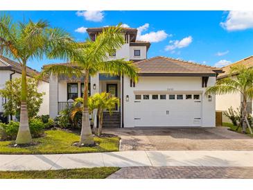 Beautiful two-story home featuring a two-car garage, tile roof, and lush tropical landscaping at 2630 Yellow Sundial Loop, Ruskin, FL 33570