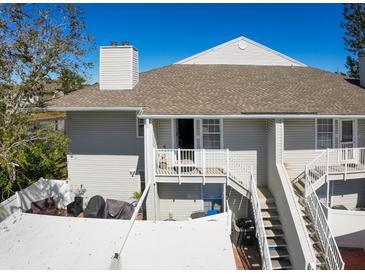 Two-story condo featuring a brown roof, white siding, a balcony, a ground-floor patio, stairs, and an outdoor grilling area at 8350 Savannah Trace Cir # 1808, Tampa, FL 33615