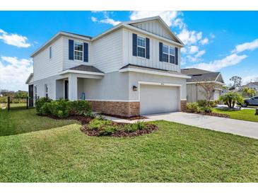 Two-story home with a two car garage, blue shutters, well manicured lawn and stone accents at 10432 High Noon Trl, Parrish, FL 34219