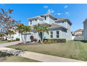 Charming two-story home featuring a well-manicured lawn, palm trees, and an attached two-car garage at 5318 Wishing Arch Dr, Apollo Beach, FL 33572