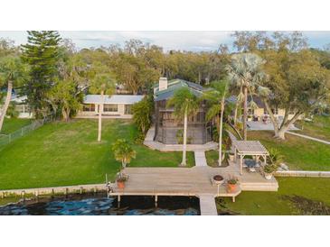 Expansive lakefront property featuring a spacious deck, charming gazebo, and lush landscaping at 680 George S St, Tarpon Springs, FL 34688