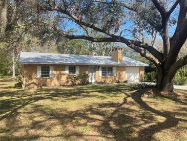 Charming brick home with a metal roof, white shutters, and a mature tree in the front yard at 3136 Hurley Rd, Valrico, FL 33596