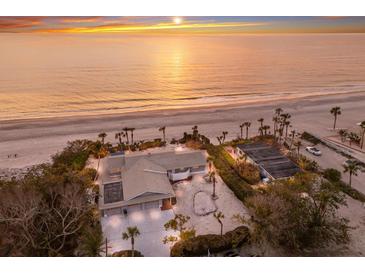 Breathtaking aerial view of the beachfront estate, showcasing the home, guest house, palm trees and private beach at 3351 Gulf Of Mexico Dr, Longboat Key, FL 34228