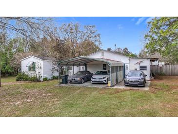 Modest single story home with a three-car carport and grassy front lawn at 8523 Hamster Dr, Zephyrhills, FL 33540