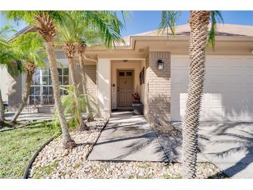 Charming single-story home features a welcoming entrance, a two-car garage, and lush landscaping with mature palm trees at 1731 Elk Spring Dr, Brandon, FL 33511