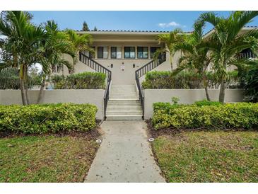 Inviting condo complex entrance with lush landscaping, palms, and stairway to the units at 1800 Mariner Dr # 9, Tarpon Springs, FL 34689