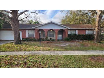 Charming red brick home featuring three arched entryways and a well-manicured lawn at 3817 Twilight Dr, Valrico, FL 33594