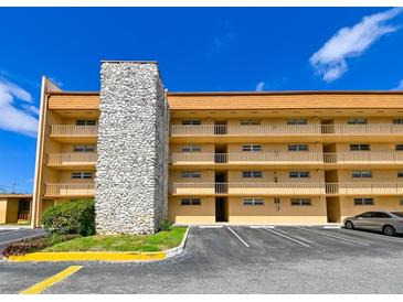 A tan condo building with parking, stone exterior design, and multiple floors of balconies at 5820 N Church Ave # 430, Tampa, FL 33614