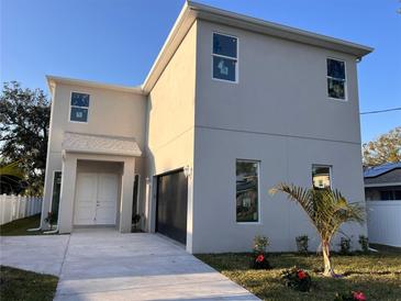 Modern two-story home featuring a neutral stucco exterior, a two-car garage and a well-manicured lawn with fresh landscaping at 3629 W Anderson Ave, Tampa, FL 33611