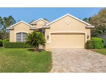 Charming home with a two-car garage, brick driveway, well-manicured lawn and verdant shrubbery at 10105 Holly Berry Dr, Weeki Wachee, FL 34613