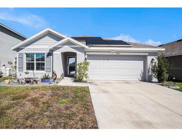 Charming one-story home featuring a well-manicured lawn, two car garage, and solar panels on the roof at 1014 Coastal Hammock Ave, Ruskin, FL 33570