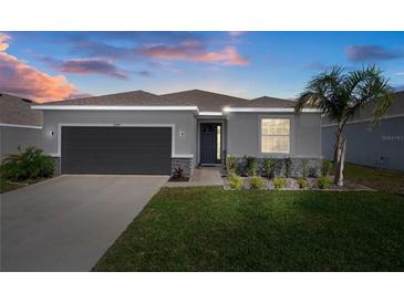 Charming single-Gathering home with a well-maintained lawn, dark grey garage door, and stone accents at 13359 Golden Lime Ave, Spring Hill, FL 34609