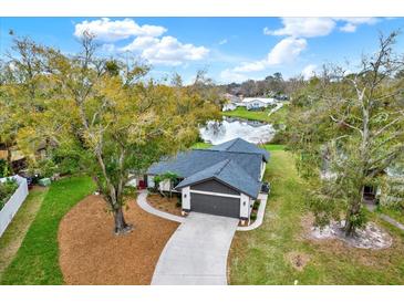 Inviting home with well-maintained landscaping and water view, complemented by a concrete driveway and gray garage door at 3944 Sprucewood Pl, Land O Lakes, FL 34639