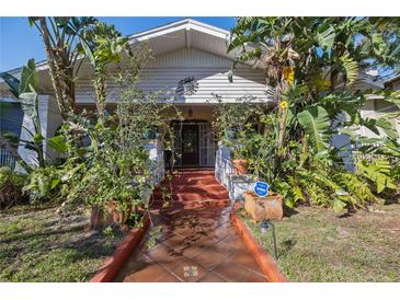 Charming home entrance with lush tropical landscaping, terracotta tile walkway, and unique architectural details at 912 E 23Rd Ave, Tampa, FL 33605