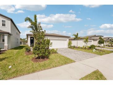 Charming one-story home boasts lush landscaping, a brick driveway, and an attached two-car garage at 129 Whiteland Bnd, Nokomis, FL 34275