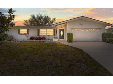 Charming single story home with a well-manicured lawn and mature trees against a lovely sunset at 1464 S Evergreen Ave, Clearwater, FL 33756