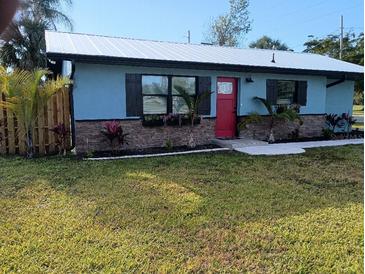Charming home with a well-maintained lawn, garden beds, and a bright red front door at 402 Mary St, Punta Gorda, FL 33950