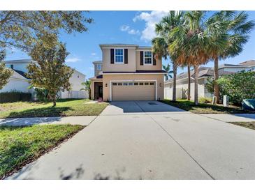 Two-story home featuring a two-car garage, manicured lawn, and mature palm trees at 7525 Forest Mere Dr, Riverview, FL 33578