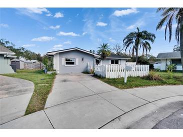 Charming single story home with a well manicured lawn, concrete driveway, and white picket fence at 415 Maplewood Cir, Oldsmar, FL 34677