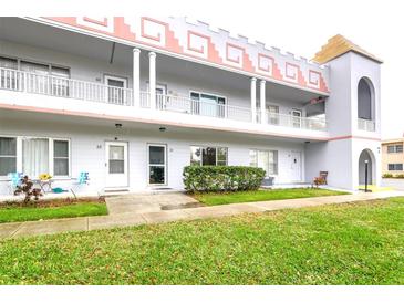 Three story condo building featuring white siding and a unique architectural design with a grassy lawn in front at 2100 World Parkway Blvd # 30, Clearwater, FL 33763