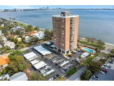 Stunning aerial view of a red brick highrise condo building next to a bay with a parking area and pool at 4015 Bayshore Blvd # 11A, Tampa, FL 33611
