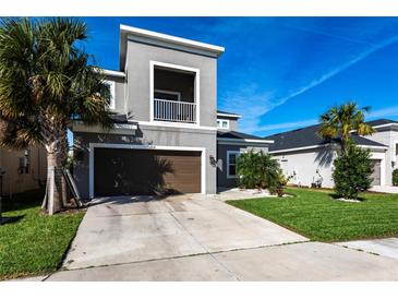 Contemporary two-story home featuring a balcony, attached garage, and a well-manicured lawn at 5934 Maidenstone Way, Palmetto, FL 34221