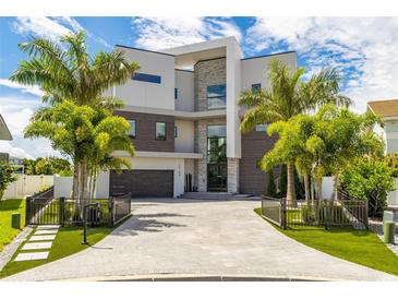 Stunning modern home featuring a beautiful stone and stucco facade with palm trees and a paver driveway at 10100 Tarpon Dr, Treasure Island, FL 33706