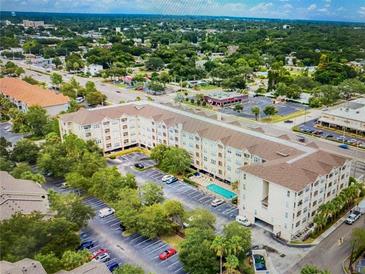Aerial view of condo community with pool, parking and green space nestled among mature trees at 1216 S Missouri Ave # 321, Clearwater, FL 33756