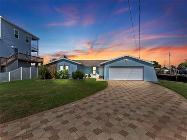 Charming single-story waterfront home with a paver driveway, attached two-car garage, and lush lawn at 13437 Lisa Dr, Hudson, FL 34667