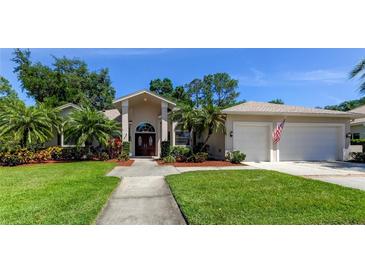 Charming single-story home with lush landscaping, mature trees, and a spacious two-car garage at 16307 Colwood Dr, Odessa, FL 33556