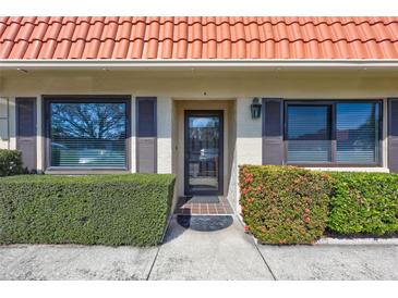 Inviting front entrance with a red tiled roof, lush green landscaping, and a modern glass door at 19029 Us Highway 19 N # 17A, Clearwater, FL 33764