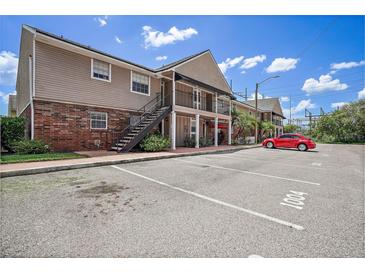 Apartment building with brick facade, balconies, and parking spots on a sunny day at 200 Country Club Dr # 1001, Largo, FL 33771