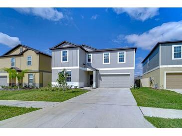 Charming two-story home featuring a well-manicured lawn, attached two car garage, and a modern gray color scheme at 22167 Tucana Way, Land O Lakes, FL 34637