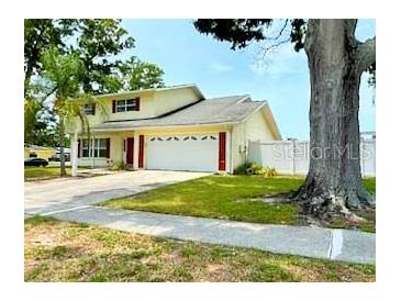 Charming home featuring a two-car garage, well-maintained lawn, and mature trees, creating a welcoming curb appeal at 2510 Cypress Bend E Dr, Clearwater, FL 33761