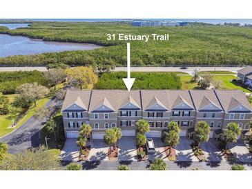 Charming townhomes featuring neutral exteriors, private garages, and lush tropical landscaping near a scenic waterfront at 31 Estuary Trl, Clearwater, FL 33759