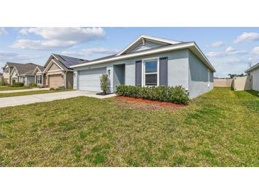 Charming single-story home with a well-manicured lawn, blue painted exterior, and neat landscaping at 8034 Broad Pointe Dr, Zephyrhills, FL 33540