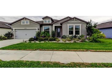 Charming single-story home featuring lush landscaping, a two car garage, and a welcoming front entrance at 12704 Palapa Loop, Spring Hill, FL 34610