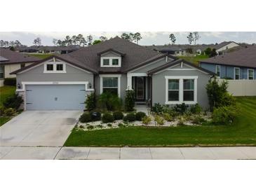 Charming one-story home featuring a manicured lawn, stone-lined garden beds, and a two-car garage at 12704 Palapa Loop, Spring Hill, FL 34610