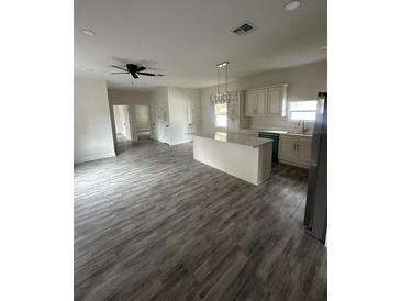 Bright, open kitchen featuring an island, modern lighting, and white cabinetry at 3012 E 149Th Ave, Lutz, FL 33559