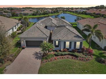 Beautiful single-story home with tile roof, lush landscaping, brick paver driveway, and picturesque water view at 4857 Tobermory Way, Bradenton, FL 34211