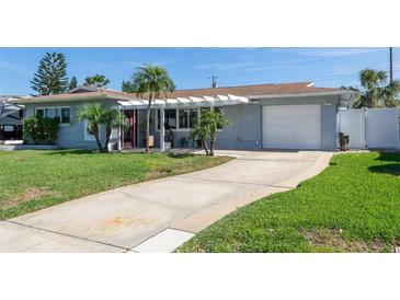 Charming single-story home featuring a well-manicured lawn, attached garage, and a welcoming covered entryway at 553 E Lake Dr, Largo, FL 33771