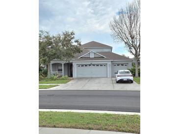 Charming home with a three car garage, lush landscaping, and a welcoming front porch at 9729 Asbel Estates St, Land O Lakes, FL 34638