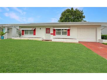 Charming single-story home featuring a well-manicured lawn, attached garage, and red window awnings at 9737 36Th N Way, Pinellas Park, FL 33782