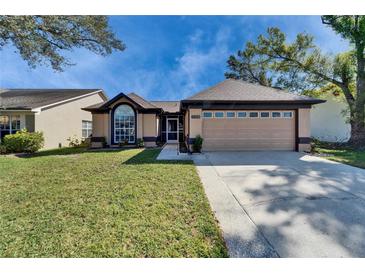 Inviting single-story home with a well-maintained lawn, a two-car garage, and attractive landscaping at 1728 Elk Spring Dr, Brandon, FL 33511