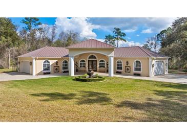 Stunning single-story home featuring manicured lawn, central fountain, a light stucco facade, and a symmetrical design at 22259 Skyview Cir, Brooksville, FL 34602