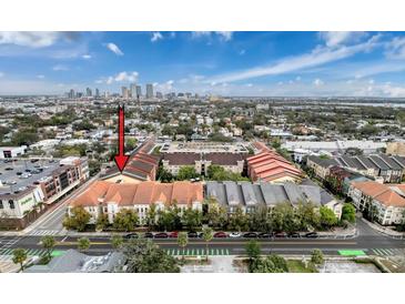 Aerial view of condo community with manicured lawns, colorful roofs, and a city skyline view at 2410 W Azeele St # 220, Tampa, FL 33609