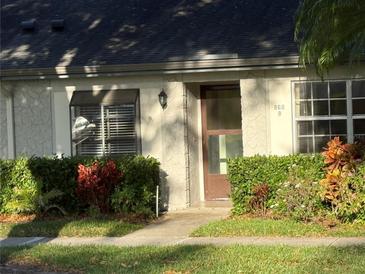 Charming townhome front entrance with a well-manicured lawn, shrubs, and exterior window treatments at 860 Glen More Ct # B, Palm Harbor, FL 34684
