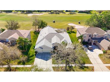 Stunning aerial view of a home overlooking a lush green golf course with a screened in pool at 18111 Diamond Cove Ct, Tampa, FL 33647