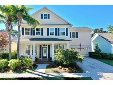 Charming two-story home featuring a manicured front yard, a covered porch, blue shutters, and an attached two-car garage at 310 Manns Harbor Dr, Apollo Beach, FL 33572