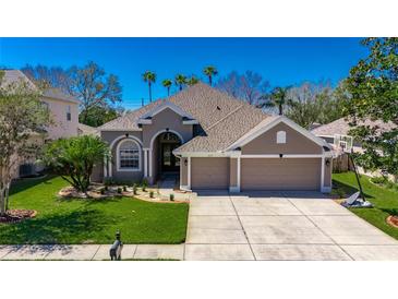 Beautiful home featuring a well-manicured lawn, palm trees, and a spacious three-car garage at 3537 Valencia Cove Court, Land O Lakes, FL 34639